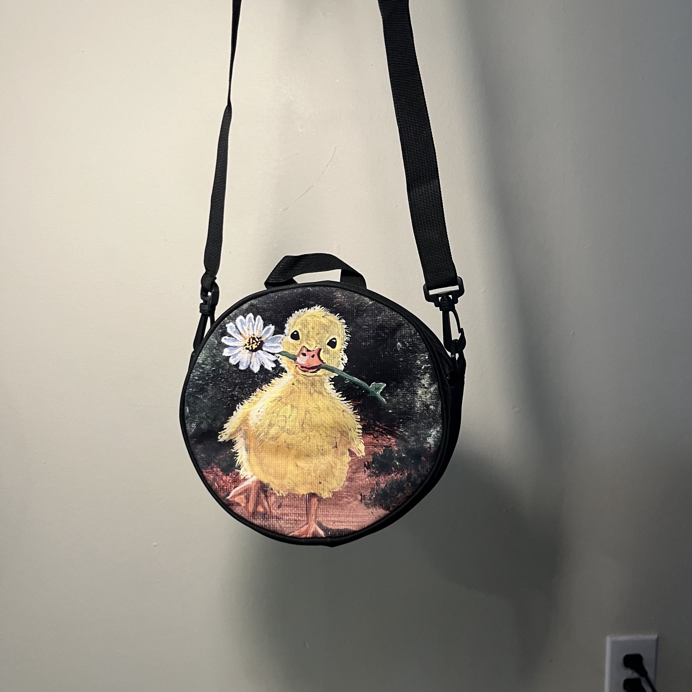Ducky Carrying Flower — Round crossbody bag, photographed by the artist