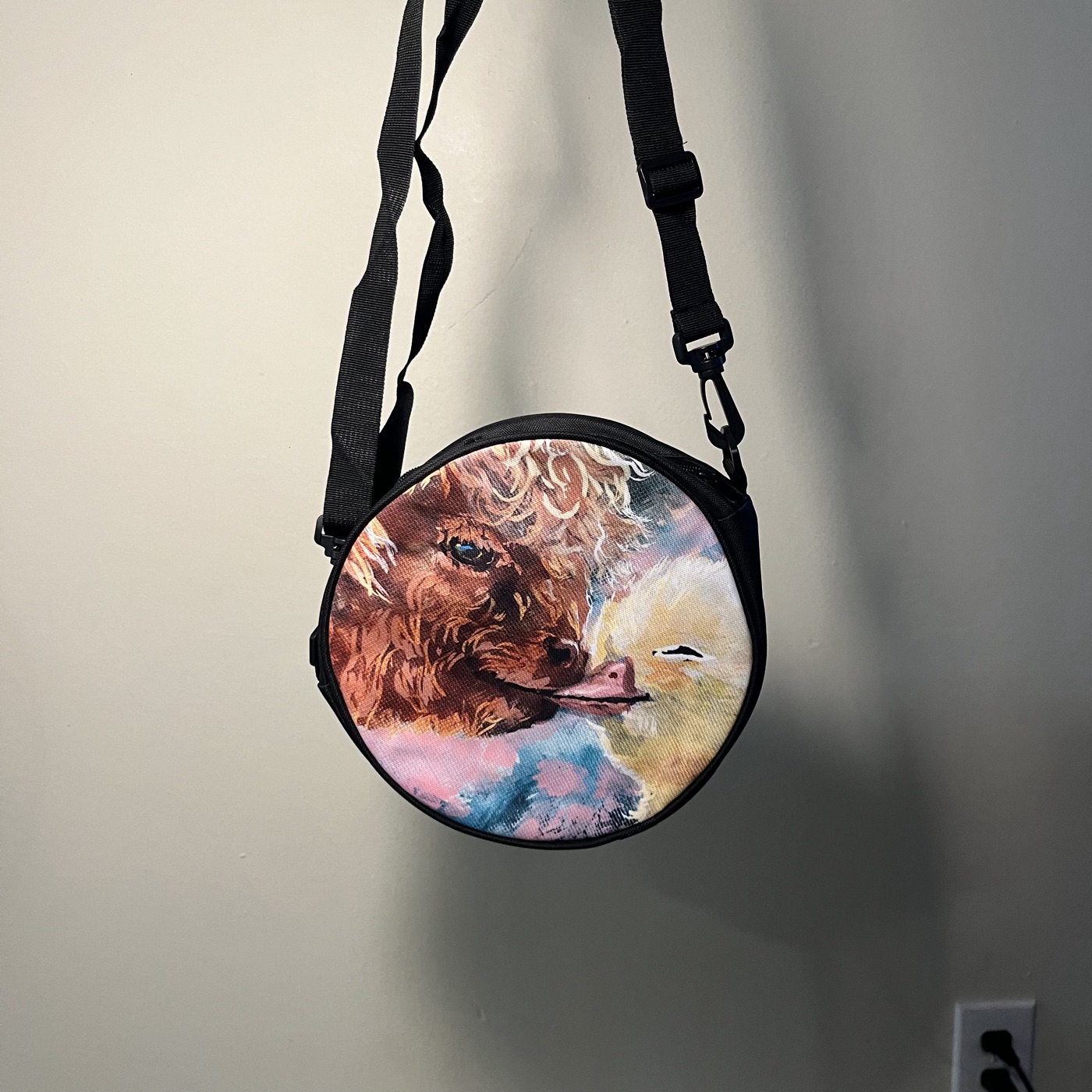 Highland Cow Kissing Ducky — Round crossbody bag, photographed by the artist